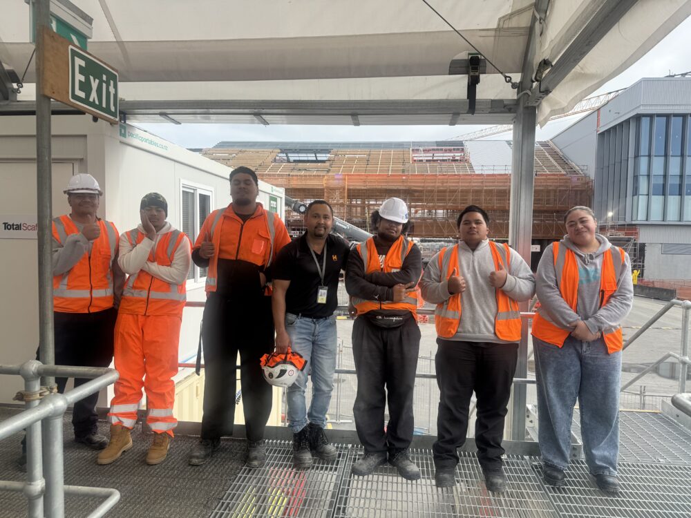 a group of people waering a Hi- vis posing and smiling at the camerafor a group photo with an intructor in the middle